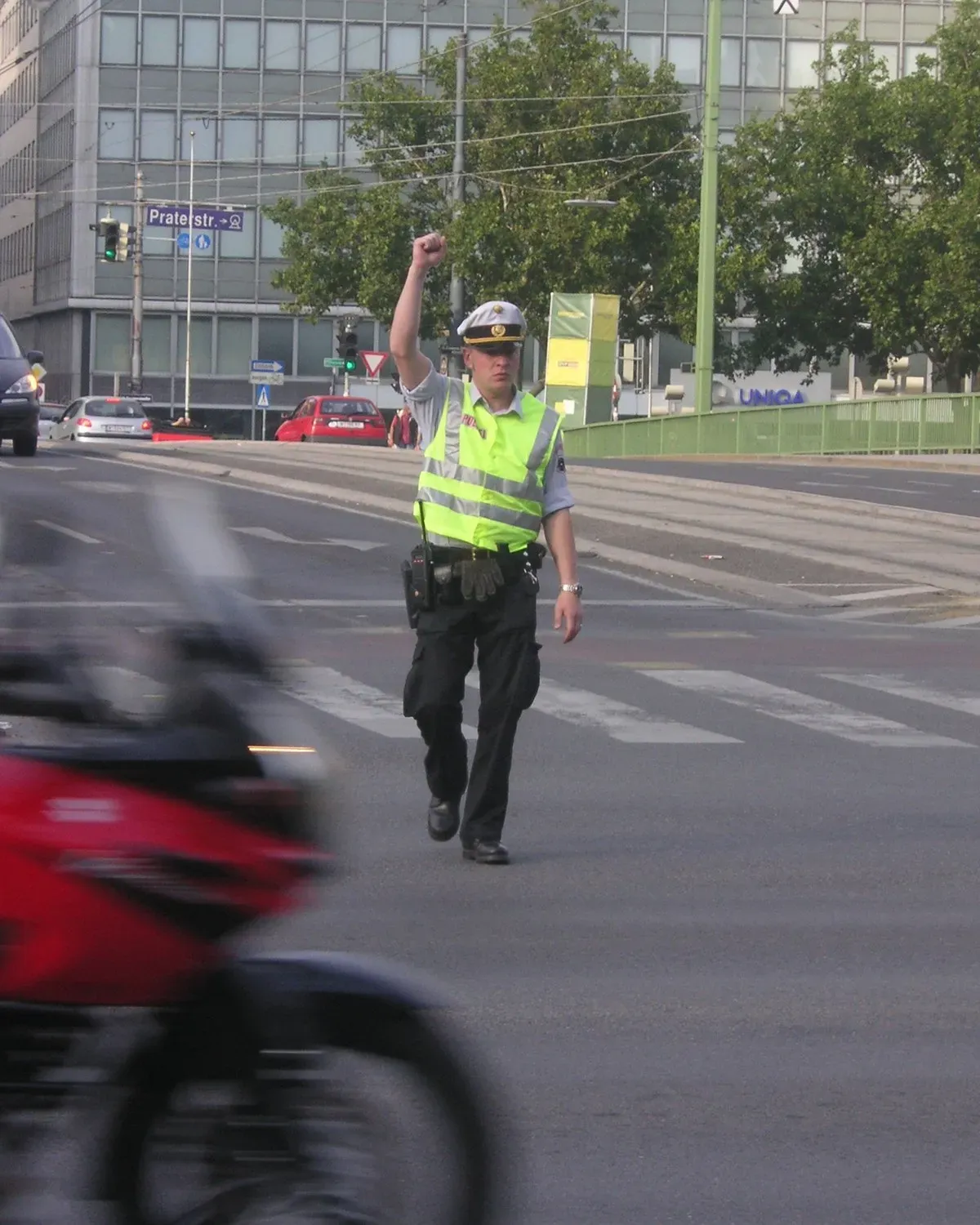 Agente de tránsito con chaleco reflectivo dirigiendo el tráfico en un paso peatonal